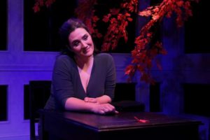 A woman sitting at a table in front of a tree.