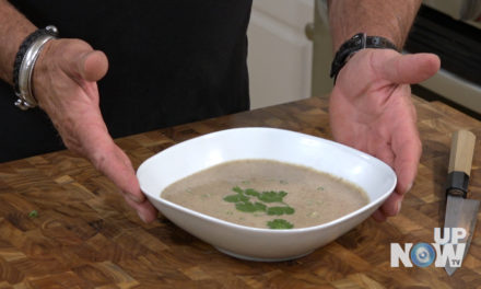A person is holding their hand over a bowl of soup.