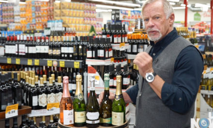 A man standing in front of a display of wine bottles.